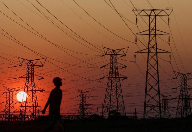 A local walks past electricity pylons during frequent power outages from South African utility Eskom, caused by its aging coal-fired plants, in Orlando, Soweto, South Africa, September 28, 2022. REUTERS/Siphiwe Sibeko