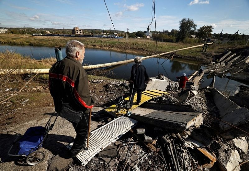 Local residents make their way through the ruins of the bridge that was destroyed during the fighting between Russian troops and Ukrainian army, amid Russia's attack on Ukraine, in Bakhmut, Donetsk region, Ukraine October 6, 2022. REUTERS/Zohra Bensemra