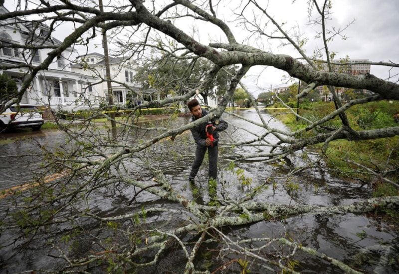 Kieran Holloway, a 25-year-old visiting from Colombia, South Carolina, volunteers to cut away a tree that fell on a flooded road, as hurricane Ian bears down on Charleston, South Carolina, U.S., September 30, 2022. REUTERS