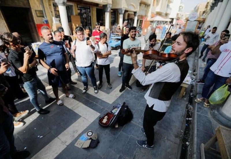 Briton Dan Hodd, 29 years old, who left Spain about a month ago to go to the COP27 in Sharm el Sheikh without flying, but mostly biking and using public transportation, plays the violin in Baghdad, Iraq October 26, 2022. REUTERS
