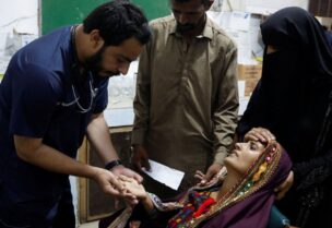 Naveed Ahmed, 30, a doctor, gives medical assistance to flood-affected woman Koonjh, 25, who is suffering from fever, at Sayed Abdullah Shah Institute of Medical Sciences in Sehwan, Pakistan September 29, 2022. REUTERS