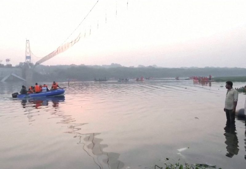 People look on as rescuers in boats work at the site of a suspension bridge collapse in Morbi town in the western state of Gujarat, India, October 31, 2022. ANI via REUTERS THIS IMAGE HAS BEEN SUPPLIED BY A THIRD PARTY INDIA OUT. NO COMMERCIAL OR EDITORIAL SALES IN INDIA