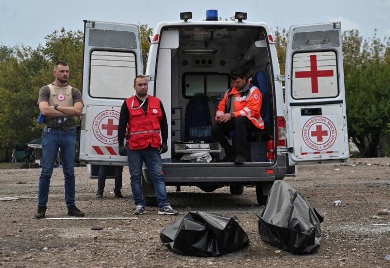 Red Cross volunteers stand next to the covered bodies of persons killed by a Russian missile strike that hit a convoy of civilian vehicles amid Russia's attack on Ukraine, after Russia held what it called referendums – votes that were denounced by Kyiv and Western governments as illegal and coercive – in Zaporizhzhia, Ukraine September 30, 2022. REUTERS/Stringer