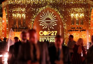 People pass in front of a wall lit with the sign of COP27 as the COP27 climate summit takes place, at the Green Zone in Sharm el-Sheikh, Egypt November 10, 2022. REUTERS/Mohamed Abd El Ghany