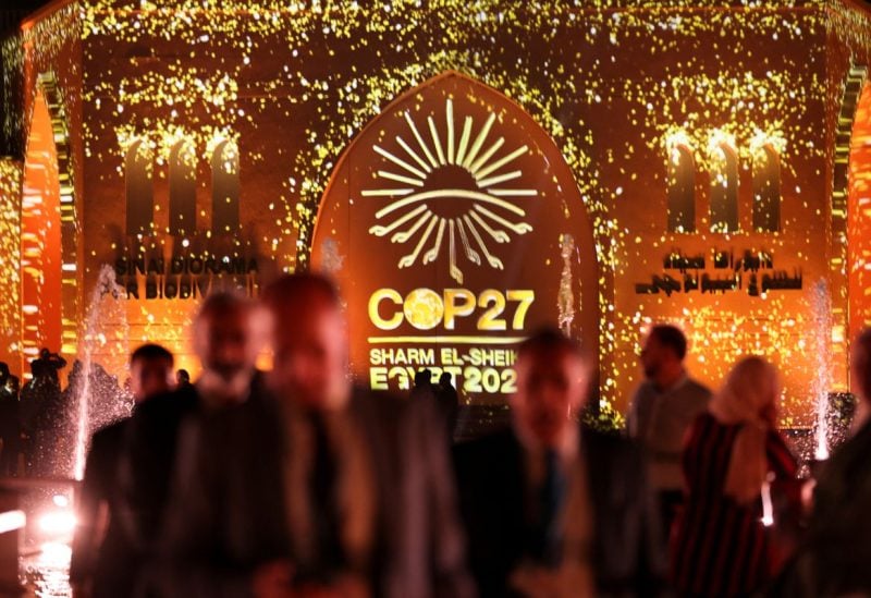 People pass in front of a wall lit with the sign of COP27 as the COP27 climate summit takes place, at the Green Zone in Sharm el-Sheikh, Egypt November 10, 2022. REUTERS/Mohamed Abd El Ghany