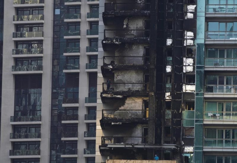 Investigators examine fire damage at the high-rise 8 Boulevard Walk in Dubai, United Arab Emirates, Monday, Nov. 7, 2022. A fire broke out early Monday morning at a 35-story high-rise building in Dubai near the Burj Khalifa, the world's tallest building. (AP Photo/Jon Gambrell)