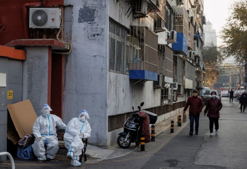 Epidemic prevention workers in protective suits sit in a locked-down residential compound as outbreaks of the coronavirus disease (COVID-19) continue in Beijing, November 23, 2022. REUTERS/Thomas Peter