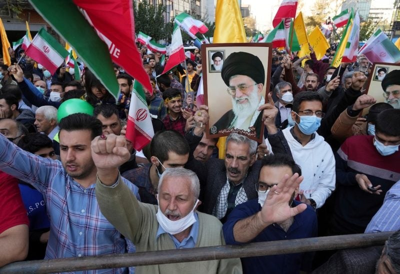 Demonstrators chant slogans as one of them holds up a poster of Iranian Supreme Leader Ayatollah Ali Khamenei during a demonstration in front of the former U.S. Embassy in Tehran, Iran, Friday, Nov. 4, 2022. Iran on Friday marked the 1979 takeover of the U.S. Embassy in Tehran as its theocracy faces nationwide protests after the death of a 22-year-old woman earlier arrested by the country’s morality police. (AP Photo/Vahid Salemi)