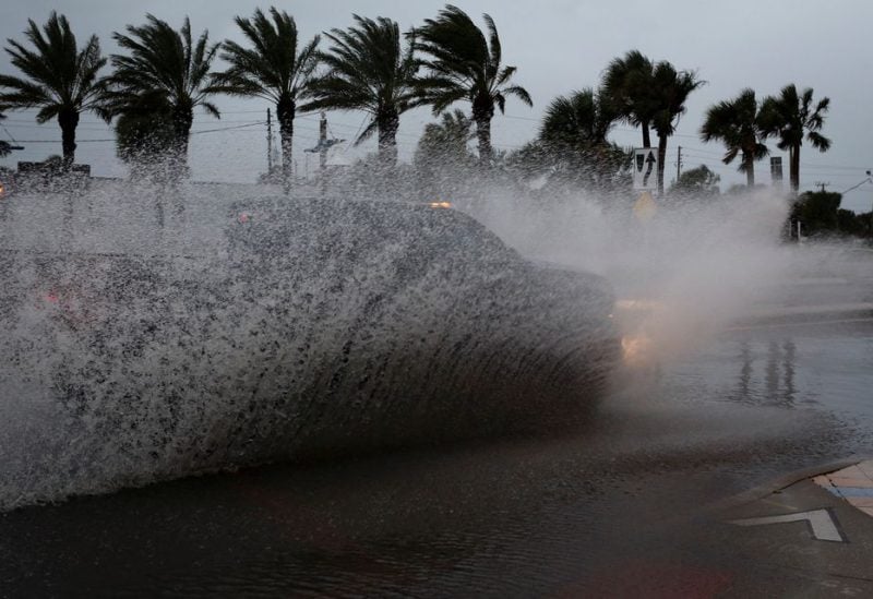 A car drives by a flooded street ahead of the expected arrival of Hurricane Nicole, in Daytona Beach, Florida, U.S., November 9, 2022. REUTERS/Marco Bello
