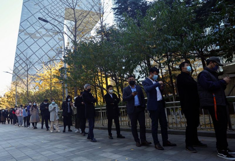 People line up to take a nucleic acid test for the coronavirus disease (COVID-19) at a testing booth near an office building in Central Business District (CBD) in Chaoyang district, Beijing, China November 15, 2022. REUTERS/Tingshu Wang