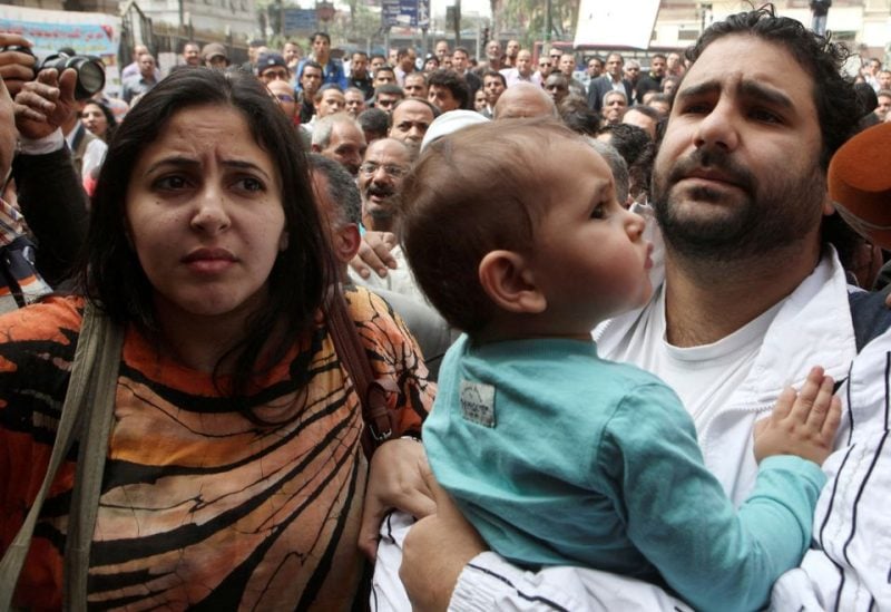 Alaa Abdel Fattah, one of the activists who was summoned by the public prosecutor on whether he had a role in the recent violent anti-Islamists protests, arrives with his wife and child to the public prosecutor's office in Cairo, Egypt March 26, 2013 - REUTERS
