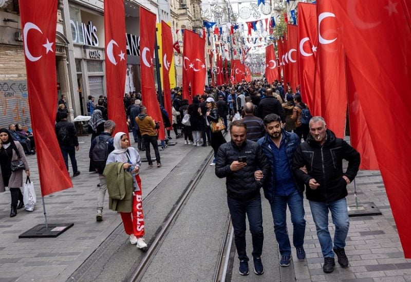People walk along Istiklal Avenue, decorated with Turkish national flags after Sunday's blast killed six and wounded dozens, in Istanbul, Turkey, November 14, 2022. REUTERS/Umit Bektas