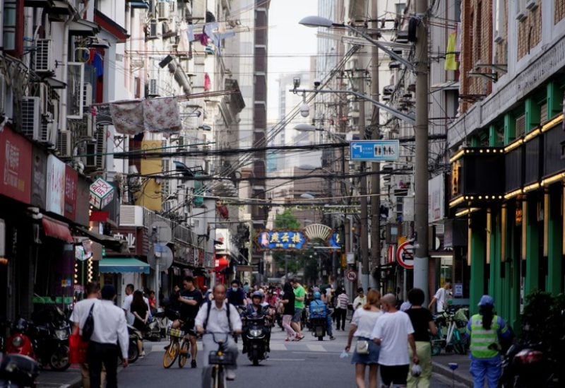 People walk and ride vehicles along a street, amid the coronavirus disease (COVID-19) pandemic, in Shanghai, China May 31, 2021. REUTERS