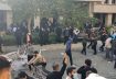 This image grab from a UGC video posted on October 30, 2022, reportedly shows a man in plain clothes (L) firing a weapon from a position among protesters during clashes at Iran's University of North Tehran. (UGC / AFP)