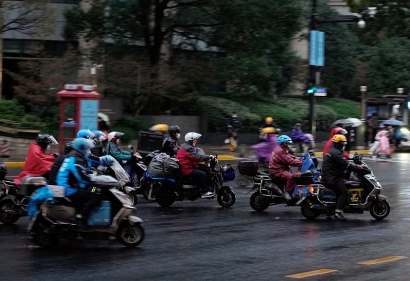 Delivery workers ride through the rain on a road, amid the coronavirus disease (COVID-19) outbreak in Shanghai, China November 30, 2022. REUTERS/Aly Song
