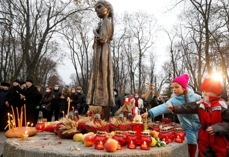 Children place ears of wheat as they visit a monument to Holodomor victims during a commemoration ceremony marking the 87th anniversary of the famine of 1932-33, in which millions died of hunger, in Kyiv, Ukraine November 28, 2020.
