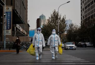 Pandemic prevention workers in protective suits cross a street as coronavirus disease (COVID-19) outbreaks continue in Beijing, December 9, 2022. REUTERS/Thomas Peter