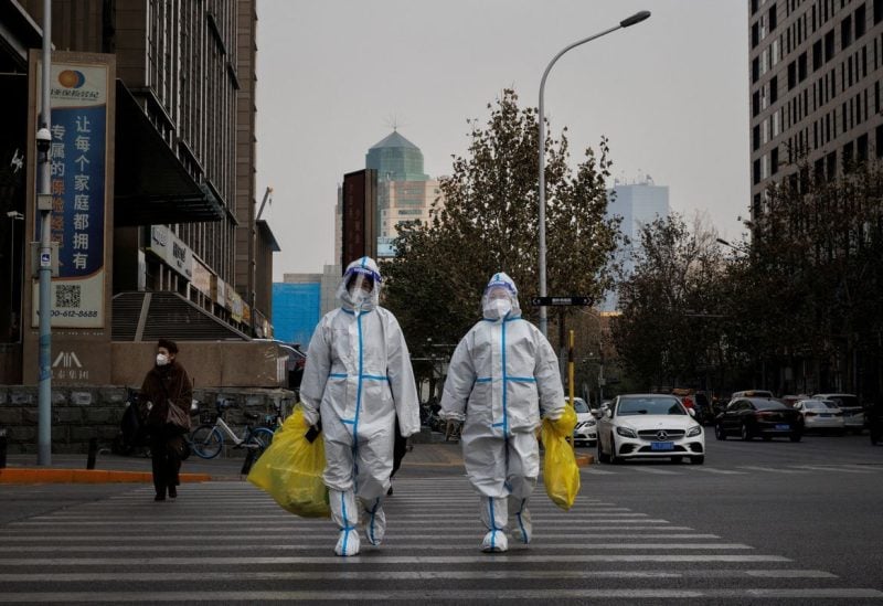 Pandemic prevention workers in protective suits cross a street as coronavirus disease (COVID-19) outbreaks continue in Beijing, December 9, 2022. REUTERS/Thomas Peter
