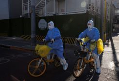 Health workers in protective suits ride bicycles while on their tour to administer nucleic acid tests as coronavirus disease (COVID-19) outbreaks continue in Beijing, December 4, 2022. REUTERS/Thomas Peter