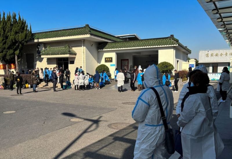 People wearing personal protective equipment (PPE) stand outside a funeral home, as coronavirus disease (COVID-19) outbreak continues, in Shanghai, China December 24, 2022. REUTERS/Staff