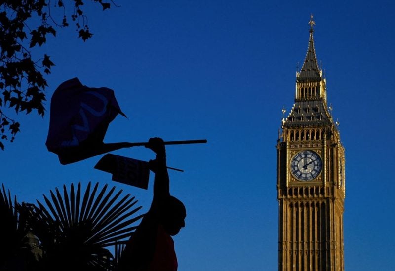 A Royal Mail worker holding flags is silhouetted as members strike over pay and conditions, outside of the Houses of Parliament in London, Britain, December 9, 2022. REUTERS/Toby Melville