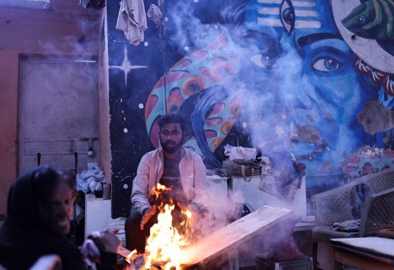 A man warms himself by a fire outside his house on a cold winter morning in New Delhi, India, December 27, 2022. REUTERS/Anushree Fadnavis