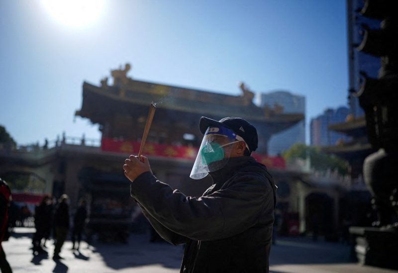 FILE PHOTO: A man wearing a protective masks and face shield worships at the Buddhist Jing'an Temple, as coronavirus disease (COVID-19) outbreaks continue in Shanghai, China, December 23, 2022. REUTERS/Aly Song/File Photo