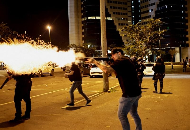 A police officer fires a shotgun as supporters of Brazil's President Jair Bolsonaro protest after supreme court justice Alexandre de Moraes ordered a temporary arrest warrant of indigenous leader Jose Acacio Serere Xavante for alleged anti-democratic acts, in Brasilia, Brazil, December 12, 2022. REUTERS/Ueslei Marcelino TPX IMAGES OF THE DAY
