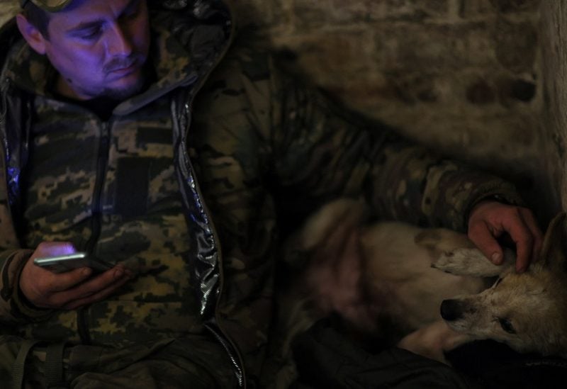 Yaroslav, 34, pets a dog while communicating target coordinates gleaned from drones to fellow service members in the field with the 24th Mechanized Brigade of King Danylo of the Ukrainian Army near Bakhmut in Ukraine, December 1, 2022. REUTERS/ Leah Millis TPX IMAGES OF THE DAY