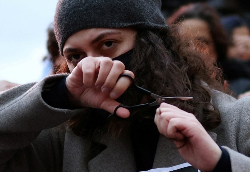 FILE PHOTO: A woman cuts her hair during the #Hair4Freedom, a mass haircutting event, led by Women's charity FiLia and anti-religious law campaign group One Law for All, to show solidarity with Iranian women, in London, Britain, November 26, 2022. REUTERS/Henry Nicholls/File Photo