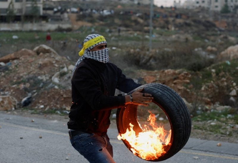 A demonstrator takes part as Palestinians hurl stones at Israeli forces during clashes following the death of senior Palestinian militant Nasser Abu Hmaid, who was jailed by Israel and died in an Israeli hospital where he has been moved to after his health conditions deteriorated, near Ramallah in the Israeli-occupied West Bank December 20, 2022. REUTERS/Mohamad Torokman