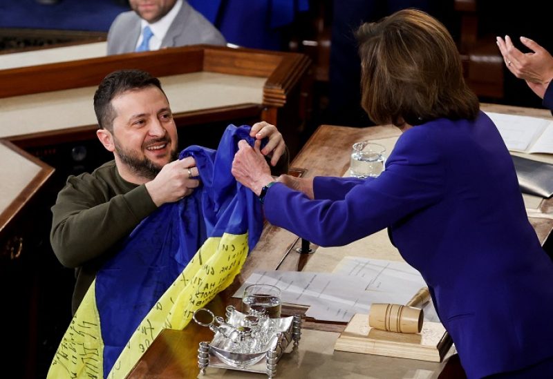 Ukraine's President Volodymyr Zelenskiy presents a Ukrainian flag given to him by defenders of Bakhmut to U.S. House Speaker Nancy Pelosi (D-CA) during a joint meeting of U.S. Congress in the House Chamber of the U.S. Capitol in Washington, U.S., December 21, 2022. REUTERS/Jonathan Ernst