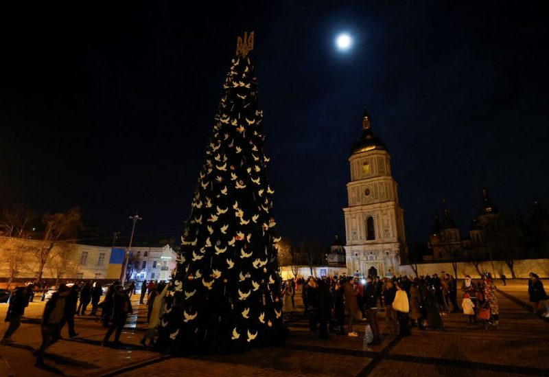 People gathered next to a Christmas tree to celebrate the New Year eve before a curfew, amid Russia's attack on Ukraine, in front of the St. Sophia Cathedral in Kyiv, Ukraine December 31, 2022. REUTERS/Valentyn Ogirenko