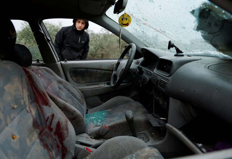 A Palestinian checks a damaged car where two militants were killed during an Israeli operation, near Jenin, in the Israeli-occupied West Bank, January 14, 2023. REUTERS/Raneen Sawafta