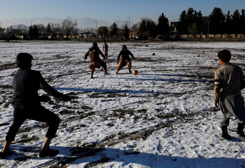 FILE PHOTO: Afghan boys play football on the snow-covered ground at the Chaman-e-Huzori field in Kabul, Afghanistan, January 13, 2023. REUTERS/Ali Khara/File Photo