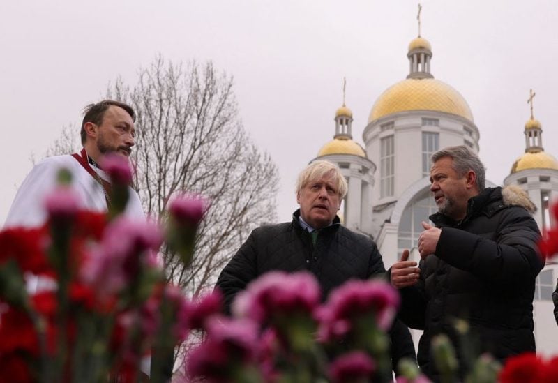 Former British Prime Minister Boris Johnson and Orthodox priest Andrew lay flowers to pay tribute to those killed amid Russia's invasion of Ukraine, during a visit to the Church of Sviatoho Apostola Andriia Pervozvannoho in Bucha, in Bucha, Ukraine January 22, 2023 - REUTERS