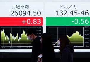 Passersby walk past electric monitors displaying Japan's Nikkei share average and the exchange rate between the Japanese yen against the U.S. dollar outside a brokerage in Tokyo, Japan, December 30, 2022. REUTERS