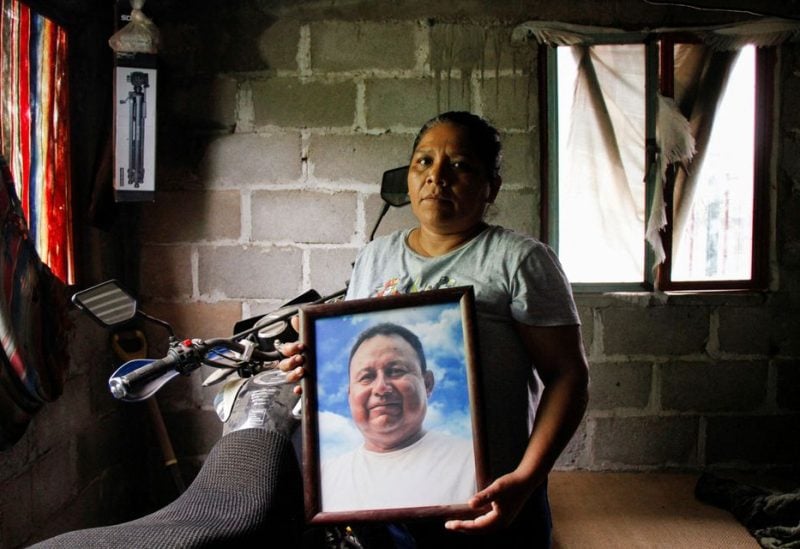 Marilu Sanchez holds a framed picture of her late husband Gustavo Sanchez, a journalist killed by assailants while riding his motorcycle with his son, at her home in Morro de Mazatan, in Oaxaca state, Mexico, October 18, 2022 - REUTERS