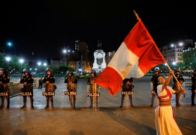 A demonstrator waves Peru's flag as security forces stand guard during a protest to demand the dissolution of Congress and democratic elections, rejecting Dina Boluarte as Peru's president, after the ouster of leftist President Pedro Castillo, in Lima, Peru January 12, 2023. REUTERS