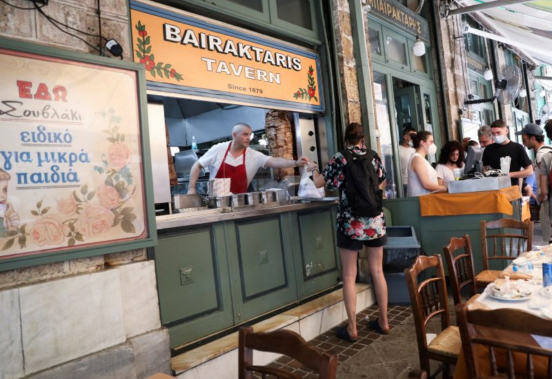 A cook gives a customer a souvlaki, a popular Greek fast food made with pieces of meat grilled on a skewer, in a restaurant, in Athens, Greece, May 27, 2022. REUTERS/Louiza Vradi/File Photo