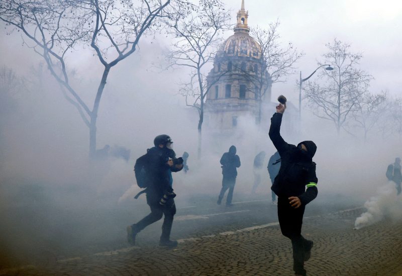 A protester throws a projectile amid tear gas during clashes near the Invalides during a demonstration against French government's pension reform plan in Paris as part of a national strike and protests in France, January 31, 2023. REUTERS