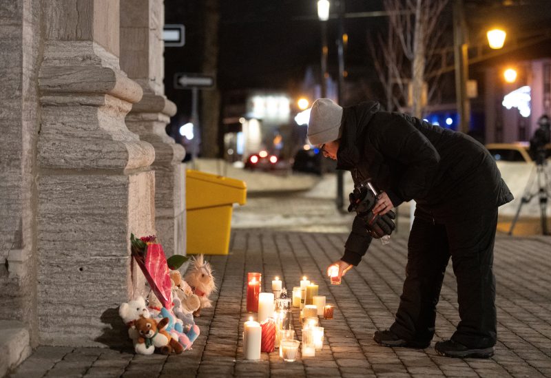 A person lights a candle during a vigil outside a church close to the site where a Laval city bus crashed into the daycare, in Laval, Quebec, February 8, 2023. REUTERS/Christinne Muschi