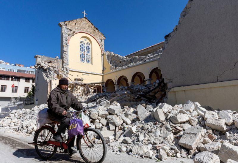 A man rides his bike along a collapsed Roman Catholic church in the aftermath of the deadly earthquake in Iskenderun, a coastal town of Hatay province, Turkey February 14, 2023. REUTERS/Umit Bektas/File Photo