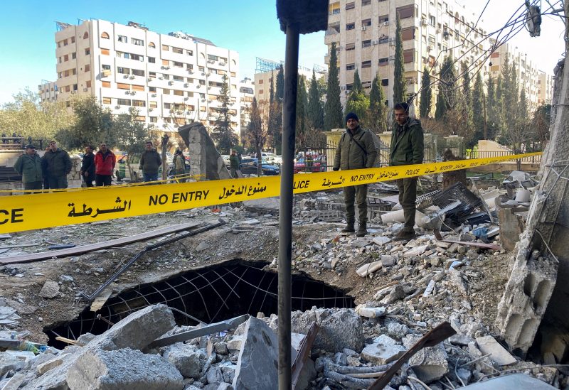 Police officers stand on the rubble of a damaged building at the site of a rocket attack, in central Damascus' Kafr Sousa neighborhood, Syria, February 19, 2023. REUTERS/Firas Makdessi