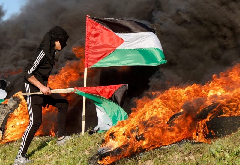 A man holds a flag as Palestinians clash with Israeli forces near the Israel-Gaza border, east of Gaza City, February 22, 2023. REUTERS/Mohammed Salem