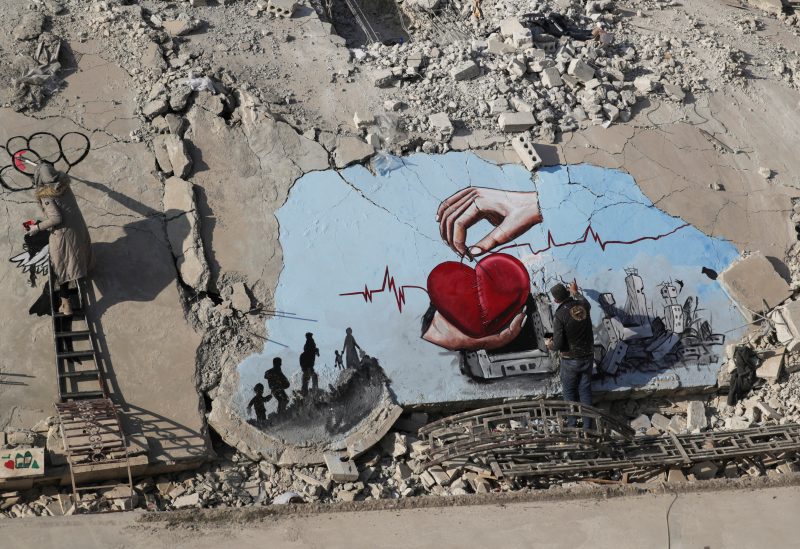 Syrian artists Aziz Asmar and Salam Hamed paint street art on the rubble of damaged buildings in the aftermath of a deadly earthquake, in the rebel-held town of Jandaris, Syria February 22, 2023. REUTERS/Khalil Ashawi