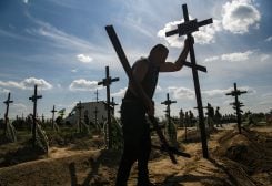 A volunteer places a cross onto a grave of one of fifteen unidentified people killed by Russian troops, amid Russia's attack on Ukraine continues, during a burial ceremony in the town of Bucha, in Kyiv region, Ukraine September 2, 2022. REUTERS/Vladyslav Musiienko