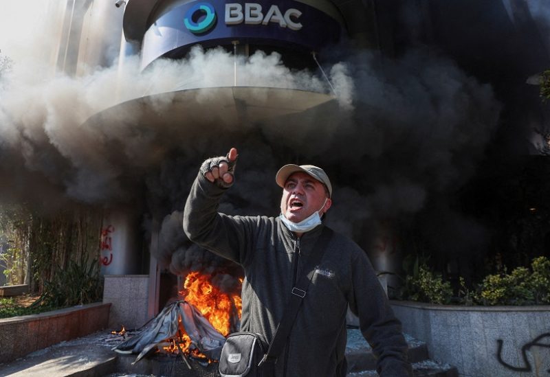 A demonstrator gestures near a bank, set on fire, during a protest organized by Depositors' Outcry, a group campaigning for angry depositors, against informal restrictions on cash withdrawals and deteriorating economic conditions in Beirut, Lebanon February 16, 2023. REUTERS/Mohamed Azakir TPX IMAGES OF THE DAY