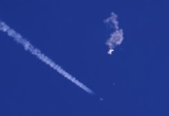 A fighter jet flies past the remnants of a large balloon after it was shot down above the Atlantic Ocean. (AFP)