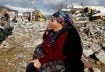 A woman gestures while sitting amidst rubble and damages following an earthquake in Gaziantep, Turkey, February 7, 2023. REUTERS/Suhaib Salem
